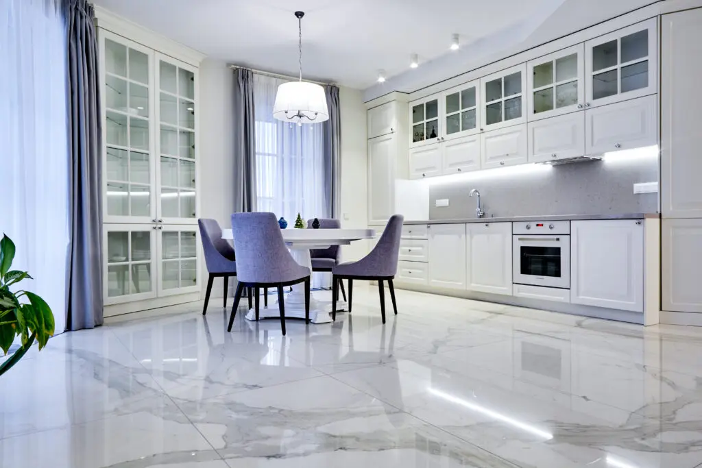 Minimalistic interior of living room in light tone with marble flooring, large windows and a table for four persons