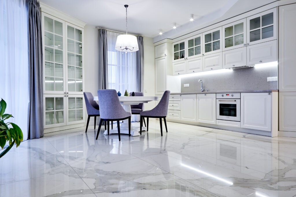 Minimalistic interior of living room in light tone with marble flooring, large windows and a table for four persons